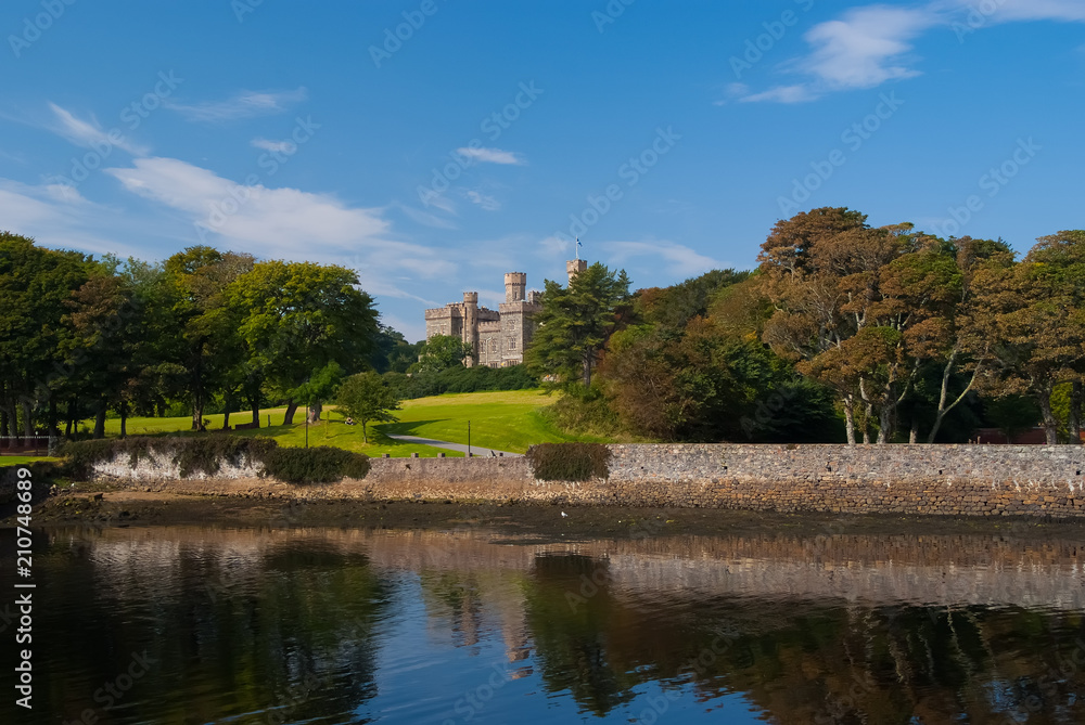 Landmark and attraction. Lews Castle in Stornoway, United Kingdom seen from sea harbor. Castle with green grounds on blue sky. Victorian style architecture and design. Summer vacation and wanderlust
