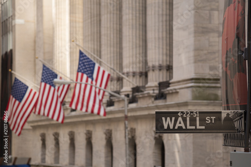 Valokuva Wall Street sign with the blurred flags of the stock exchange as background