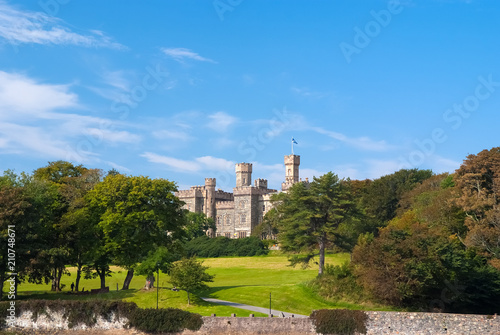 Lews Castle on estate landscape in Stornoway, United Kingdom. Castle with green grounds on blue sky. Victorian style architecture and design. Landmark and attraction. Summer vacation and wanderlust photo