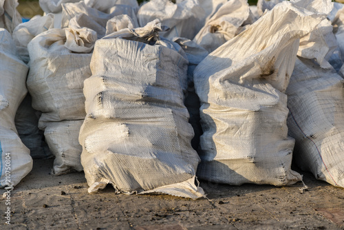 Group of filled plastic woven sacks with harvested crops, packing of goods for transportation and storage in a warehouse, polypropylene bags