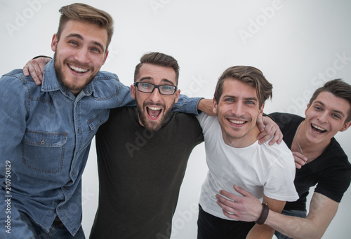 Four cheerful young guys stand and hug