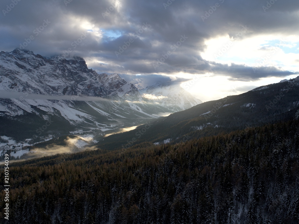 Fototapeta premium drone flying above pine tree forest on cold winter morning with sunset and alps mountain range in background