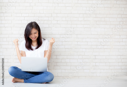 Beautiful of portrait asian young woman excited and glad of success with laptop computer, girl sitting working on cement brick background, career freelance business concept. photo