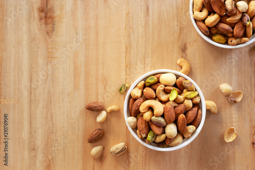 mixed nuts in white ceramic bowl on wooden background