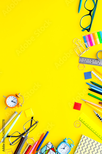 Education concept. Stationery for school pupil mockup with glasses and notebook on yellow background top view copy space