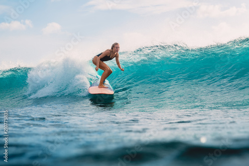 Beautiful surfer girl on surfboard. Woman in ocean during surfing. Surfer and wave photo