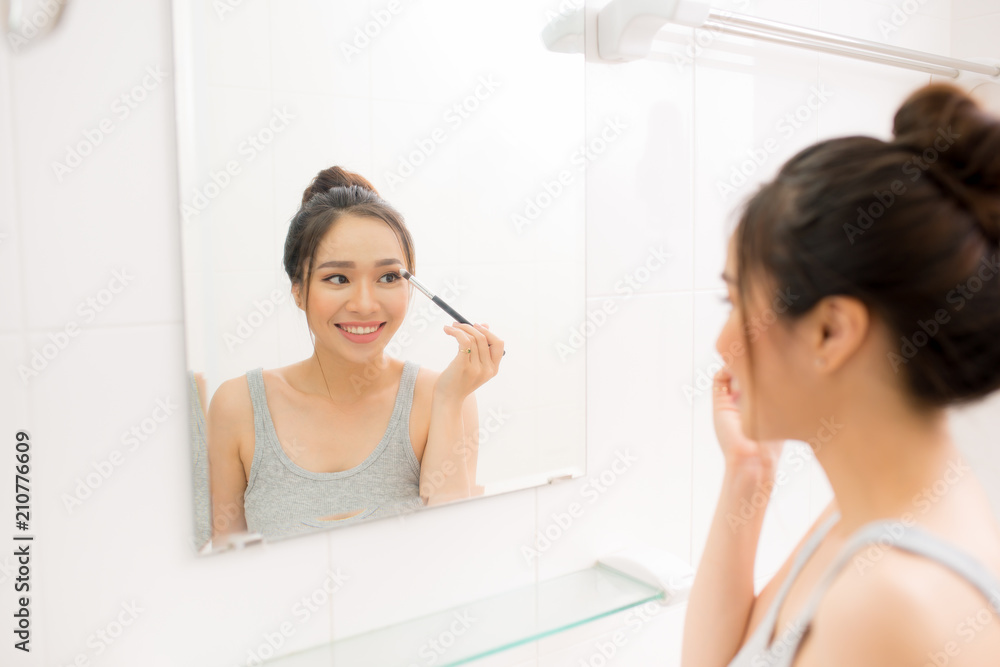 Beautiful woman applying makeup blusher in her bathroom Beautiful woman applying makeup blusher in her bathroom