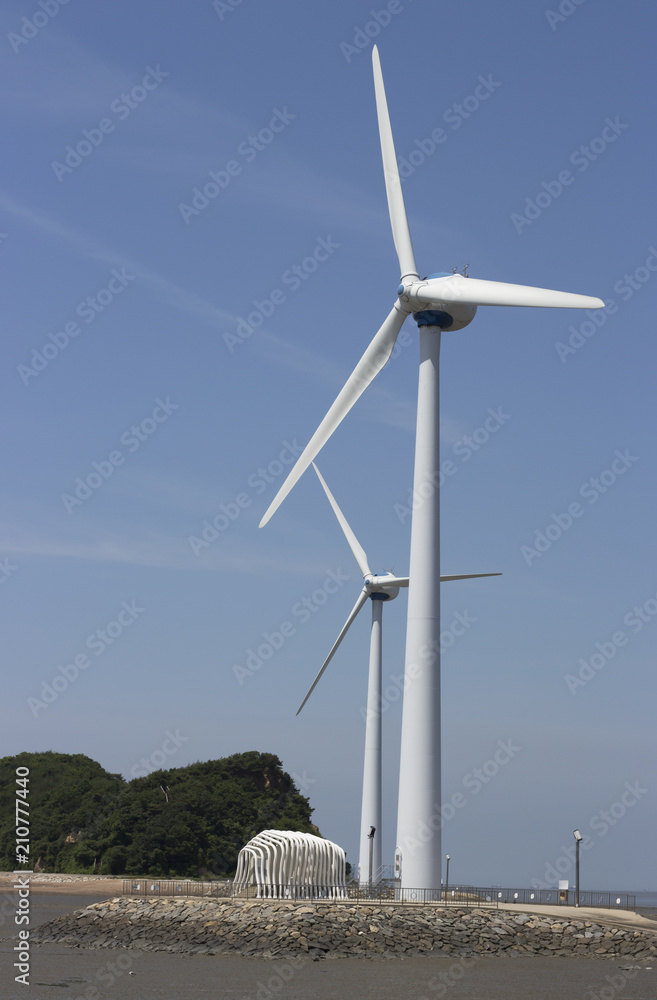 Two Wind turbines generating electricity against the sky in South Korea, concept alternative energy Two Wind turbines generating electricity against the sky in South Korea, concept alternative energy