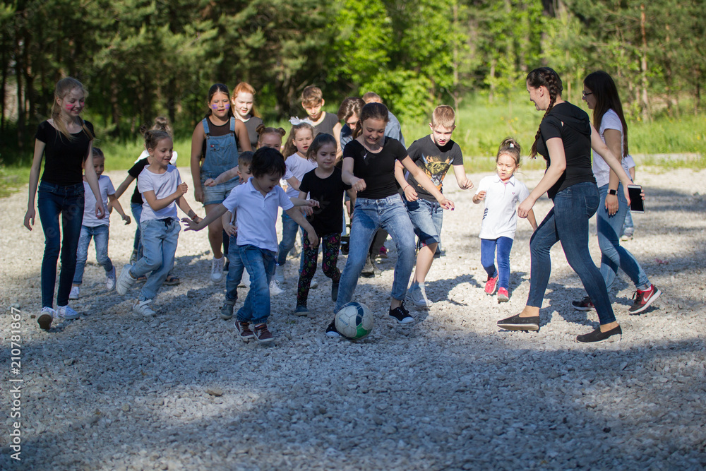 Team of teenagers playing yard football with a children team at sunny day Team of teenagers playing yard football with a children team at sunny day