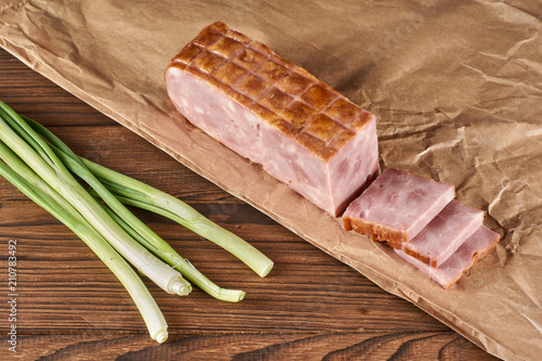 ham on kraft paper with green onion on a wooden background photo