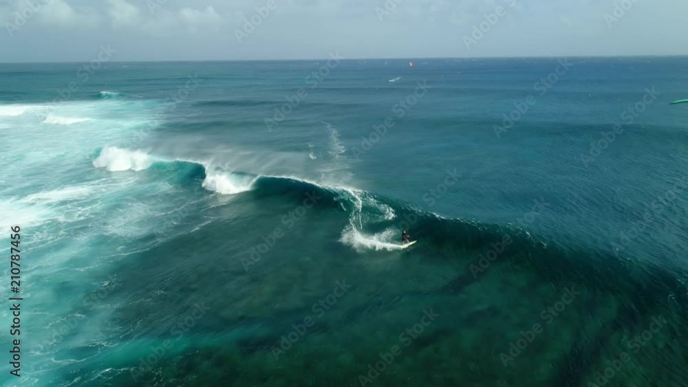Kitesurfing Le Morne, Mauritius. Drone view flying backwards in front of kite surfer. Kite surfer surfing crystal clear water, perfect waves. Aerial view