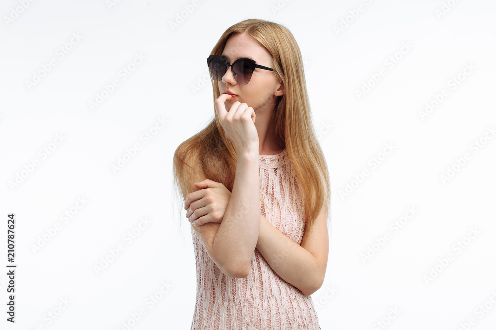 Fototapeta premium Portrait of an emotional stylish girl who thinks of something, the model poses in glasses on a white background for advertising