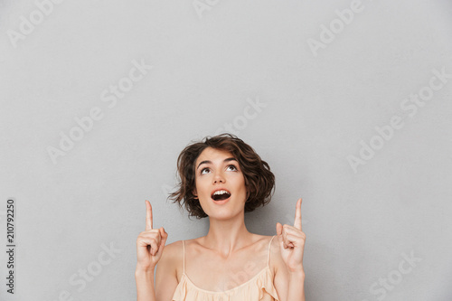 Portrait of a surprised young woman pointing fingers up photo