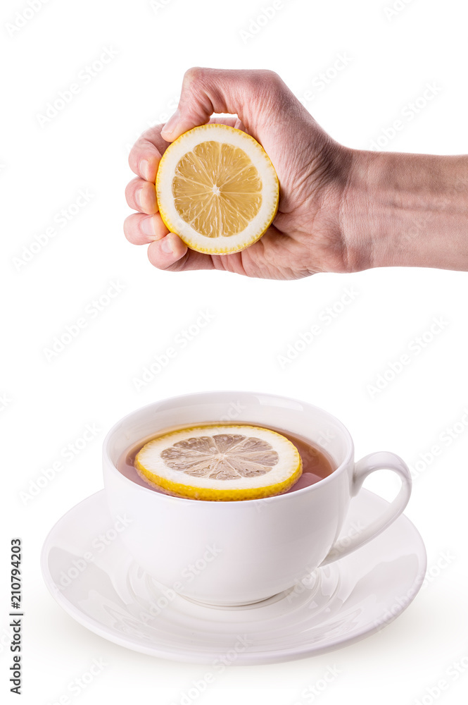 White cup on saucer of tea hand squeezes a lemon White cup on saucer of tea hand squeezes a lemon