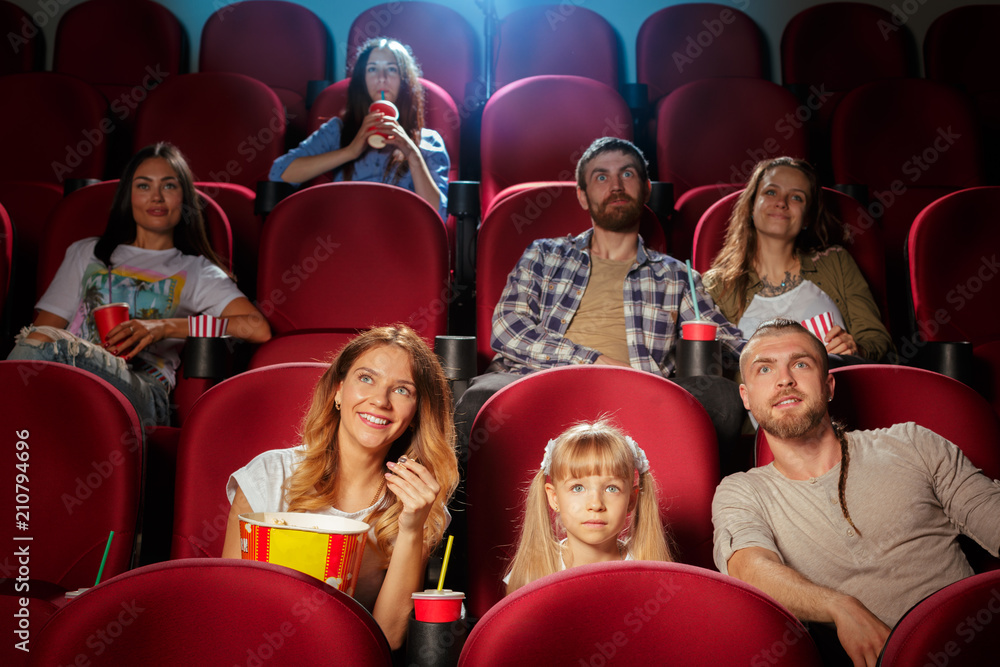 Group of friends sitting in movie theater with popcorn and drinks Group of friends sitting in movie theater with popcorn and drinks