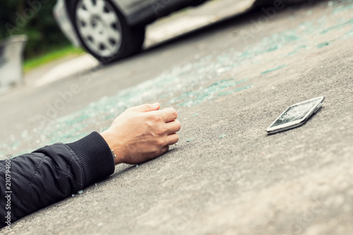 Close-up of hand of traffic victim and smartphone on the street