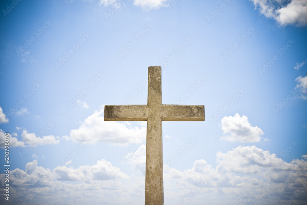 Concrete christian cross against a bright sky - concept image with copy space