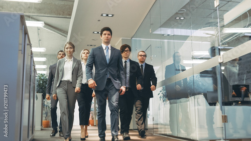 Diverse Team of Delegates/ Lawyers Confidently Marching Through the Corporate Building Hallway. Multicultural Crowd Of Resolute Business People in Stylish Marble and Glass Offices. photo