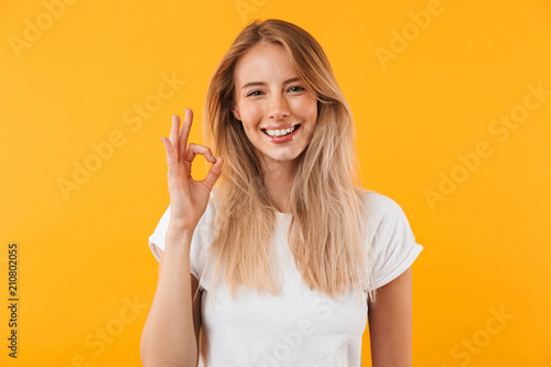 Portrait of a happy young blonde girl showing ok gesture photo