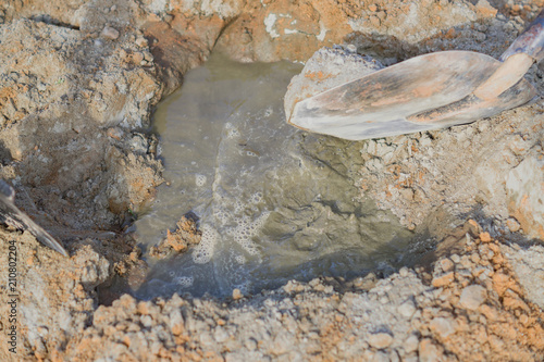  pooring water to the mixture of sand and cement. Making cement at construction cite, photo