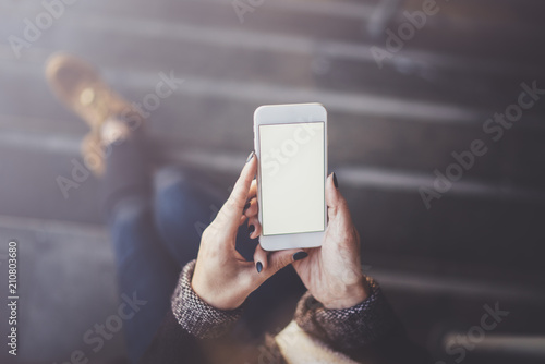 Woman holding hands smartphone and texting message.Female hands using mobile phone.Closeup on blurred background.Flares, bokeh effects. Mock-up.