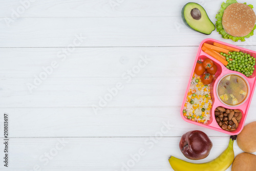 top view of tray with kids lunch for school and fruits on wooden table