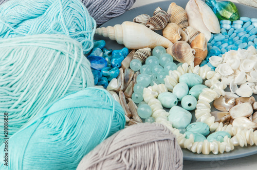 Knitting threads and gray plate with beads and seashells