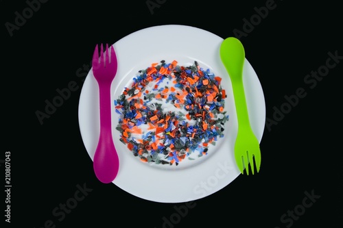 Restrictions on the use of plastics.Food and Drink contains poisonous substances leaking from plastics.nCrushed multicolored plastic pieces on white plate and multifunctional cutlery.
