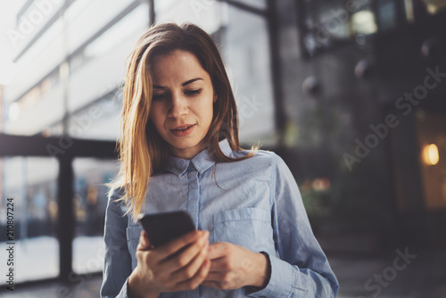 Wallpaper Mural Charming young business woman talking with partner via mobile phone while standing at modern business center. Torontodigital.ca