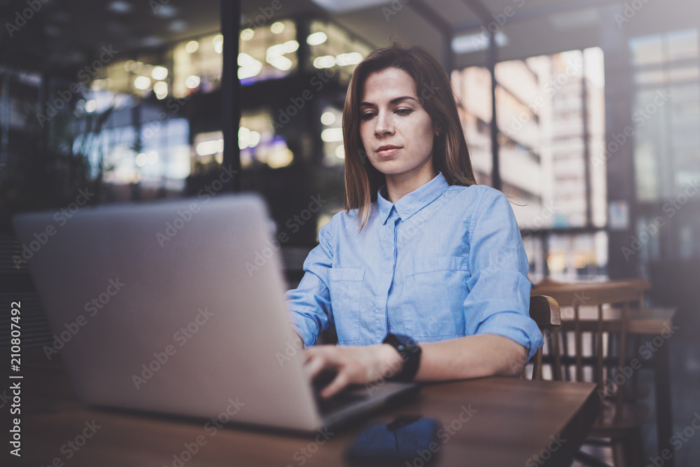Young pretty girl working on laptop and using mobile smartphone at her workplace at modern office center.Horizontal.Blurred background. Young pretty girl working on laptop and using mobile smartphone at her workplace at modern office center.Horizontal.Blurred background.