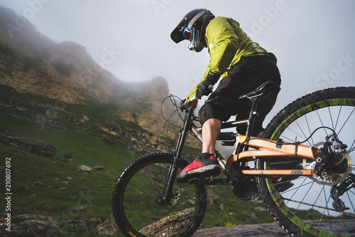Fototapeta Naklejka Na Ścianę i Meble -  Extreme mountain bike sports athlete man in helmet riding outdoors against a background of rocks. Lifestyle. Trial