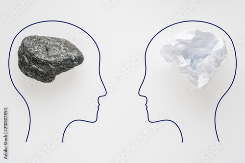 Heads of two people with crumpled paper brain shape and stone brain shape. Two people with different thinking. Rational and irrational thinking. Idea and teamwork.