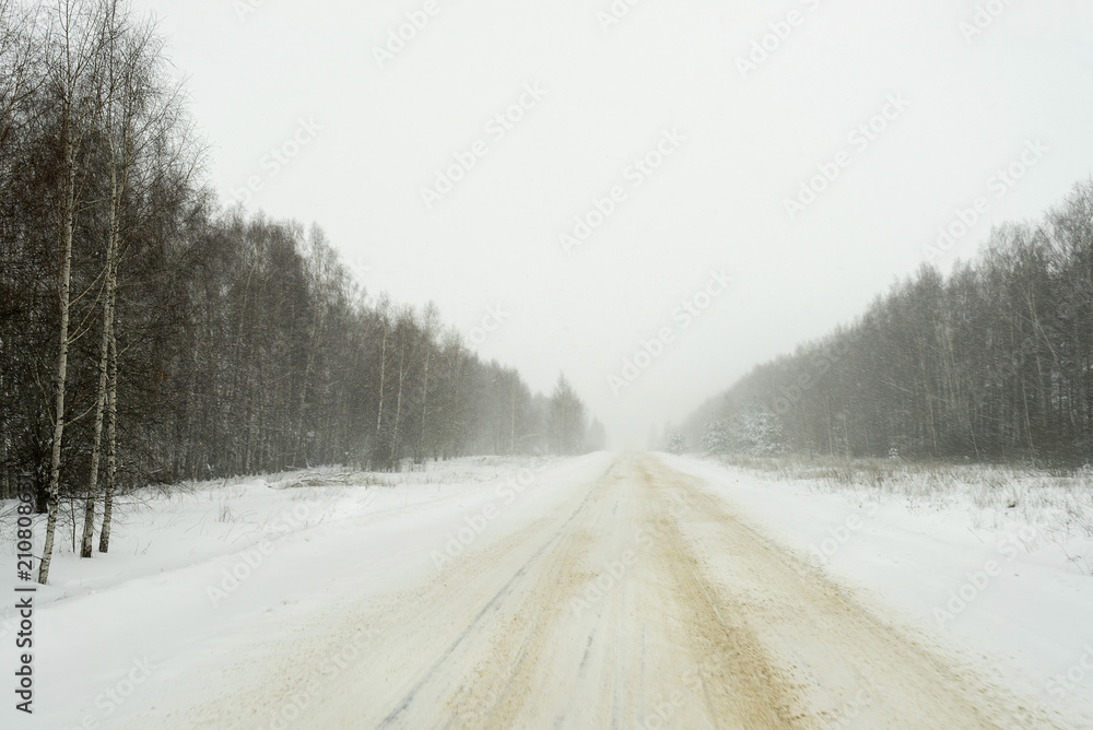 Vanishing snow-covered straight highway surrounded by winter forest recedes. Nizhegorodsky region, Russia.
