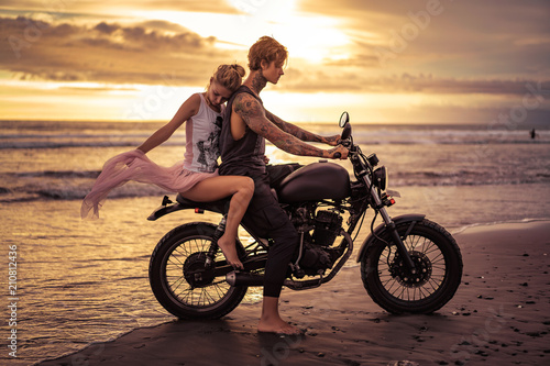 sensual boyfriend and girlfriend on motorbike on ocean beach during sunrise