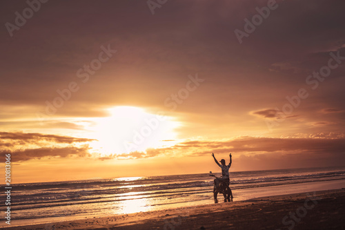 biker standing near motorbike with hands up and looking at beautiful sunrise