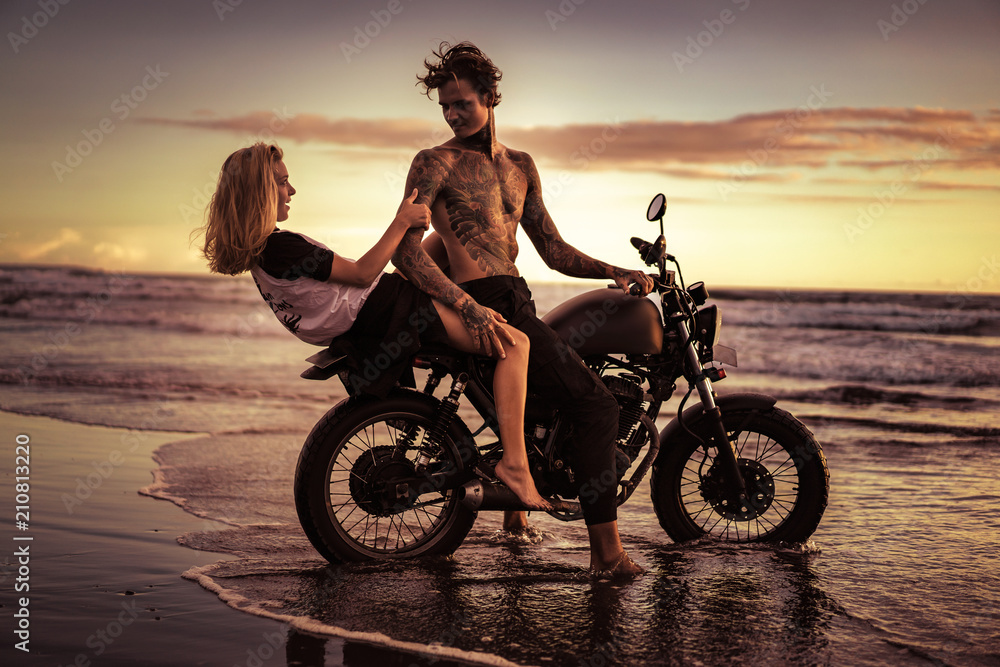 Fototapeta couple having fun on motorcycle at ocean beach