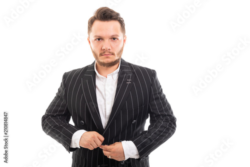 Portrait of young business man buttoning up jacket.