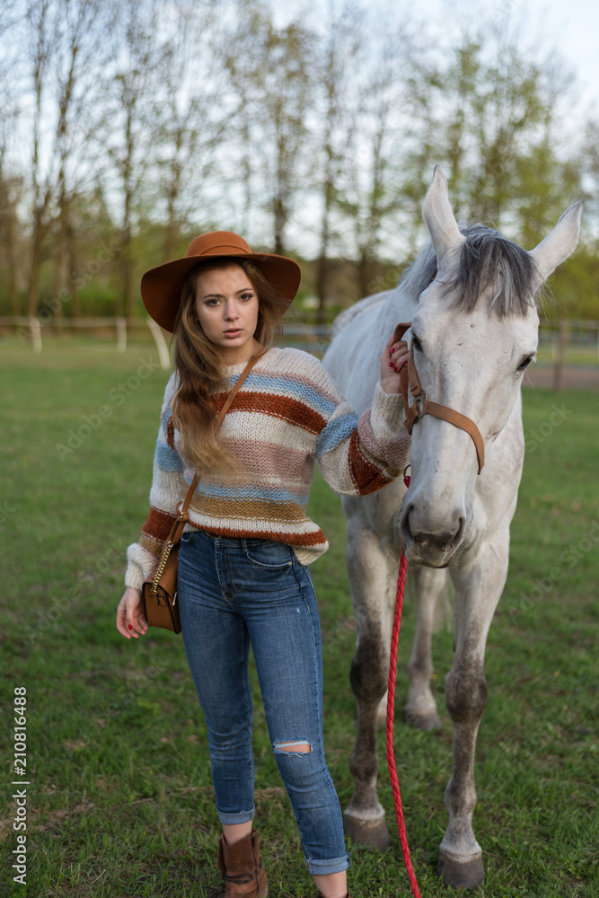 Beautiful young woman with white horse outdoors. Love animal. Cowgirl in jeans. Happy girl Beautiful young woman with white horse outdoors. Love animal. Cowgirl in jeans. Happy girl