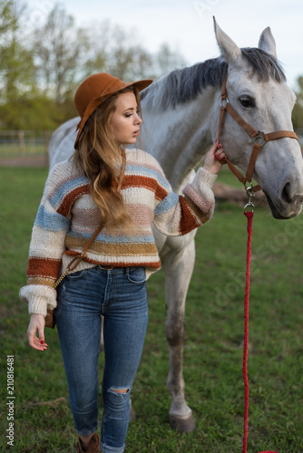 Beautiful young woman with white horse outdoors. Love animal. Cowgirl in jeans. Happy girl