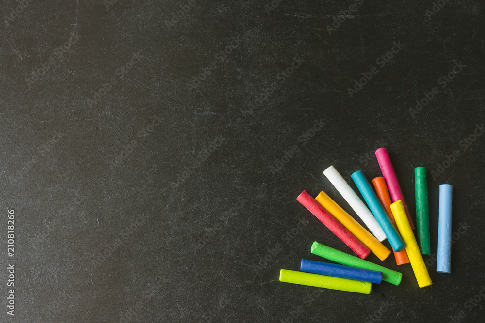 Bright pastel crayons lying on a black school board. Children's creativity. Concept- back to school. Copy space. Bright pastel crayons lying on a black school board. Children's creativity. Concept- back to school. Copy space.