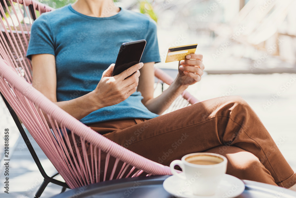 Young woman holding credit card and using smartphone. Travel and online shopping concept Young woman holding credit card and using smartphone. Travel and online shopping concept