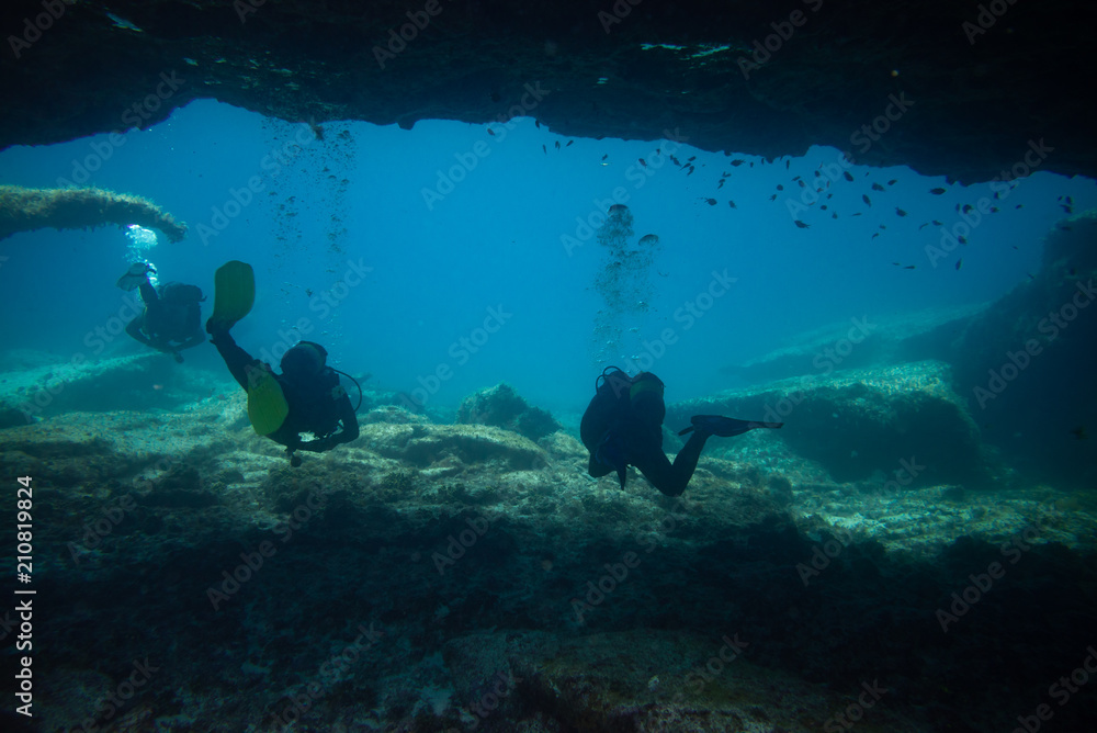 Fototapeta premium divers comes out of an underwater cave