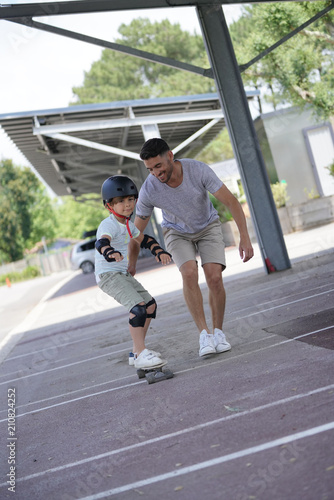 Young boy with dad learning how to skate