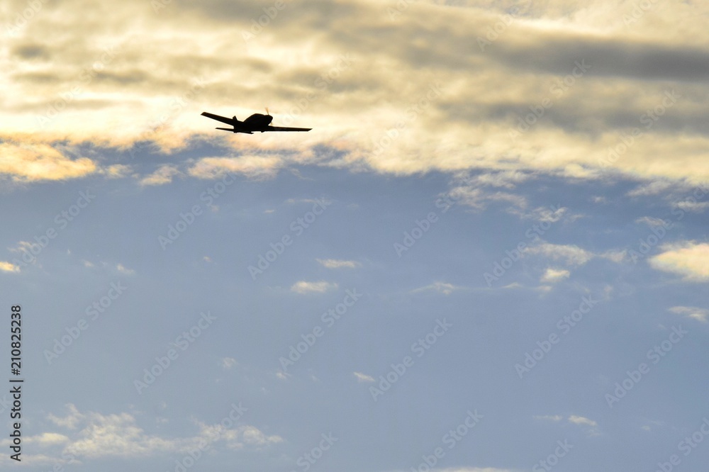 single engine low wing  propeller airplane silhouette flying in the evening sky 