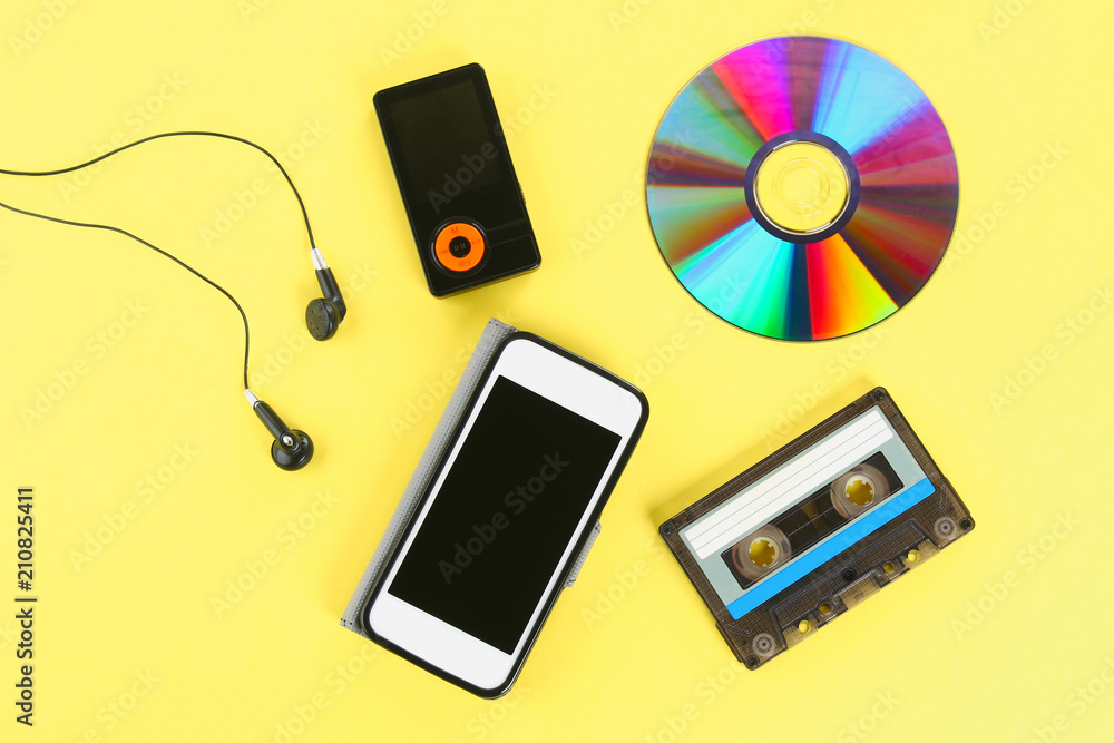The concept of the evolution of music. Cassette, CD-disk, mp3 player,  mobile phone. Vintage and modernity. Music support. Photos | Adobe Stock