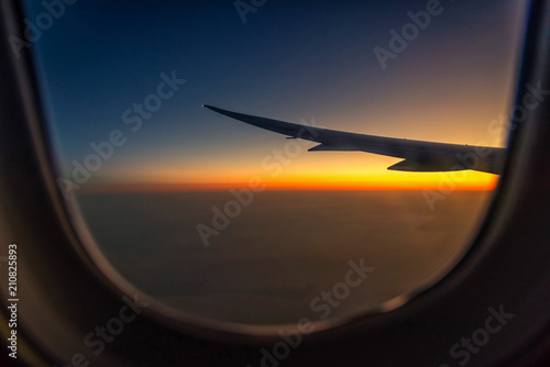 Silhouette wing of an airplane at sunrise view through the window.