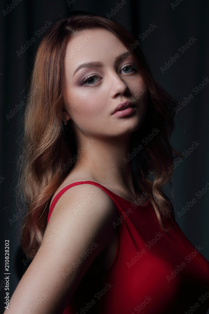 Charming brunette in a red dress posing on a black background. Charming brunette in a red dress posing on a black background.