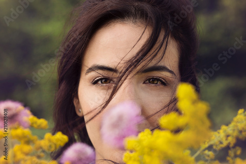 Donna caucasica sorride dietro a dei fiori di campo photo