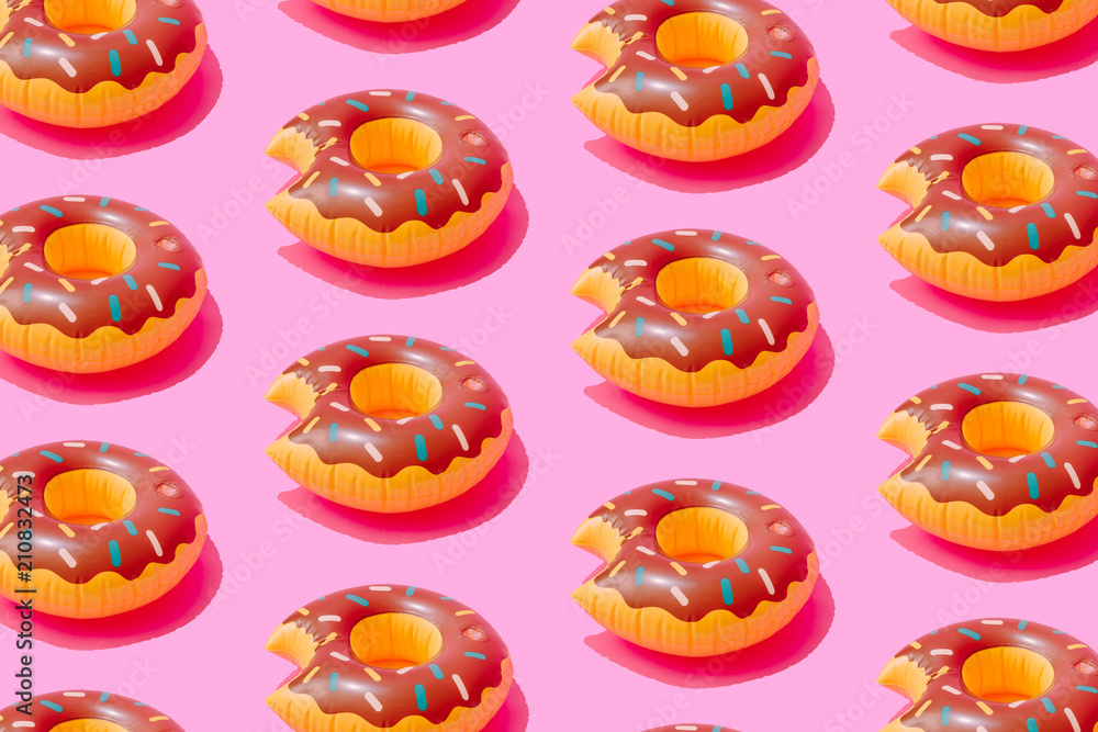 Inflatable doughnut pool toy pattern  on pastel pink background. Minimal summer concept.