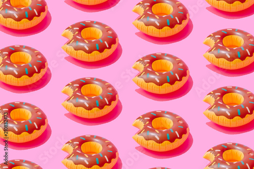 Inflatable doughnut pool toy pattern on pastel pink background. Minimal summer concept.